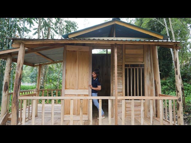 The girl make the door and install doors and windows--Build wooden cabin live with nature