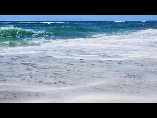 Waves lapping on a sandy beach at noon