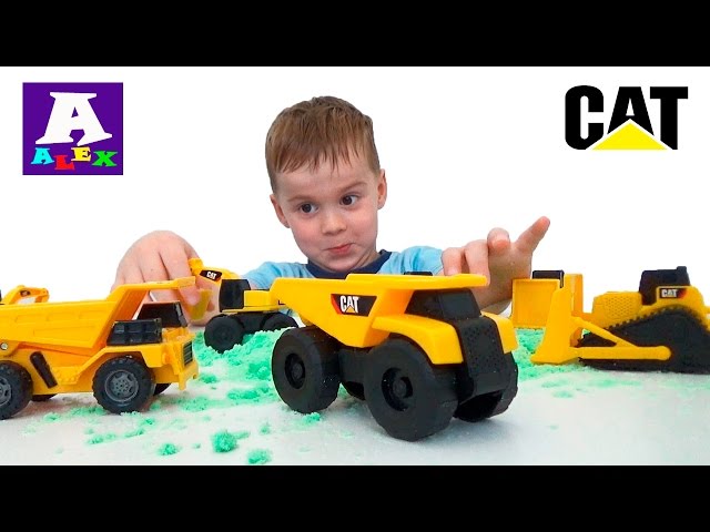 Play caterpillar toy cars on the sand. Unpacking construction machines CAT dump truck, bulldozer