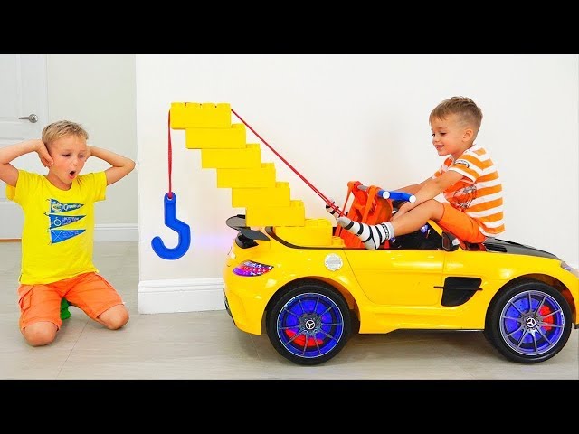 Vlad und Nikita spielen mit einem Spielzeug-Abschleppwagen für Kinder